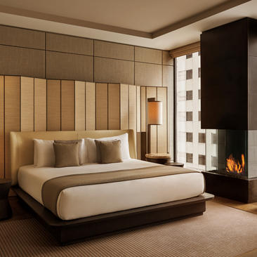 Deluxe bedroom at Aman New York featuring a contemporary bed with warm wood paneling and city views.