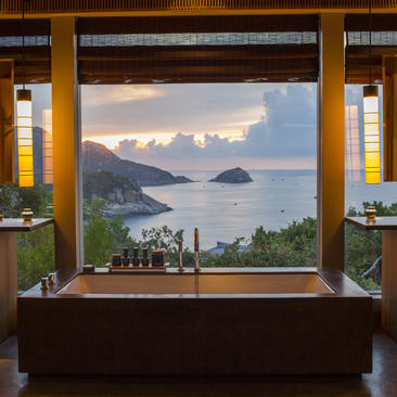 Amanoi framed by wooden columns, overlooking coastal waters and distant islands at dusk.