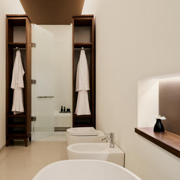 Cuarto de baño de la suite Alcova Tiepolo en el hotel Aman Venice, con lavabo redondo blanco y almacenamiento de madera.