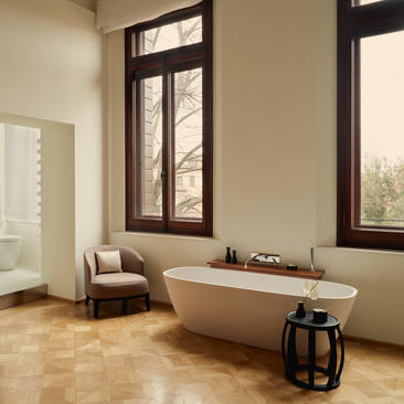 Salle de bains avec baignoire autoportante et fenêtres donnant sur Venise à Aman Venice.