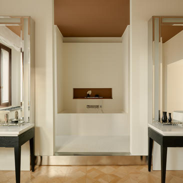 安缦威尼斯酒店浴室，浴缸上方嵌入式壁炉，两侧配置黑色洗手台。