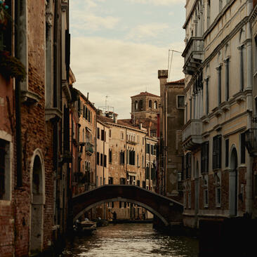 Venetian canal lined with weathered palazzo buildings and a stone bridge at Aman Venice, Italy.