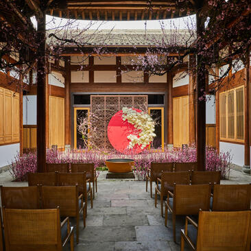 Wedding ceremony space at Amanyangyun with red circular floral installation and traditional wooden architecture.