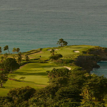 Vue aérienne du parcours de golf d'Amanera, bordé par des eaux turquoise.