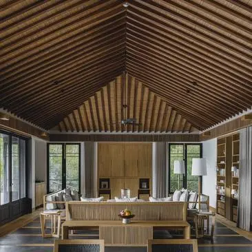 Interior of Amanoi's open-plan dining pavilion with wooden vaulted ceiling and floor-to-ceiling windows.