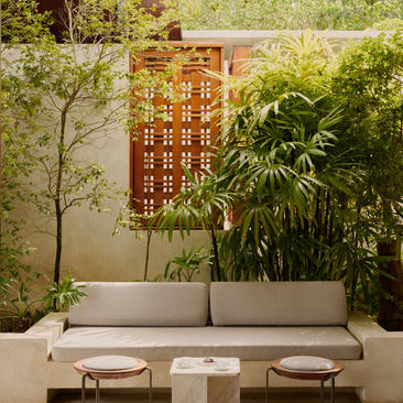 Exterior courtyard at Amanera resort with seating area, geometric timber screen, and lush tropical plants.
