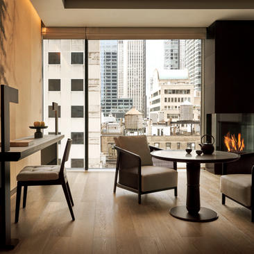 Interior da Grand Suite no Aman New York, com sala de estar, lareira e vista para Manhattan.
