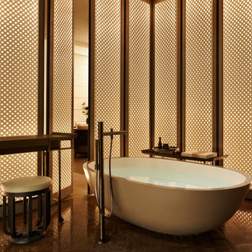 Bagno della Grand Suite ad Aman New York con vasca ovale bianca e parete rivestita in legno.