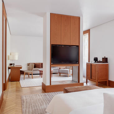 Garden view room at Aman Sveti Stefan with warm wood furnishings and television integrated into wooden cabinetry.