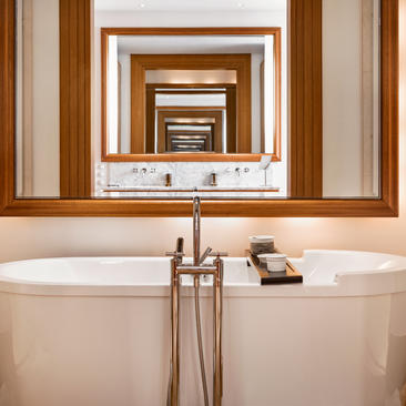 Freestanding bathtub with brass fixtures and mirrored wall at Aman Sveti Stefan.