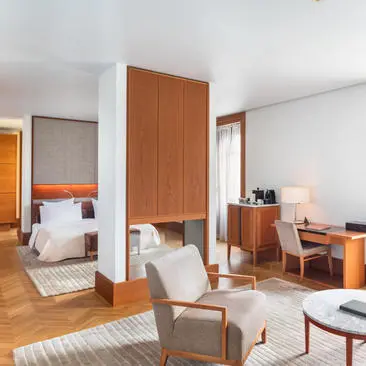 Spacious principal bedroom at Aman Sveti Stefan with wooden furnishings, separate seating area, and sea views.