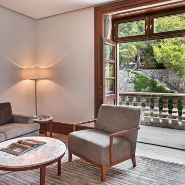 Reading area at Aman Sveti Stefan with armchair, floor lamp, and sea views through open doors.