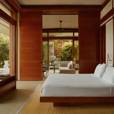 Bedroom with terracotta walls, wooden beams and bed overlooking courtyard at Amanera resort.