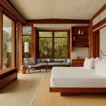 Spacious two-bedroom casa bedroom with warm wood furnishings, large windows overlooking greenery, and serene natural light at Amanera resort.
