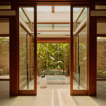 Puertas de madera y vidrio abiertas hacia un patio ajardinado en una casa de dos dormitorios de Amanera.