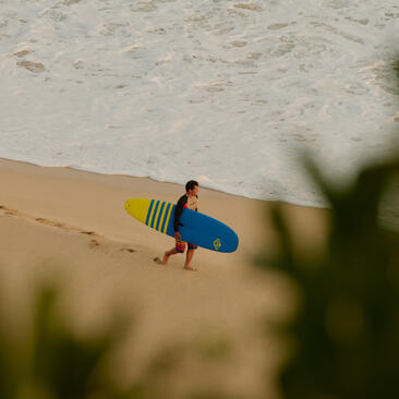 Surfer avec planche bleue sur la plage d'Amanera.
