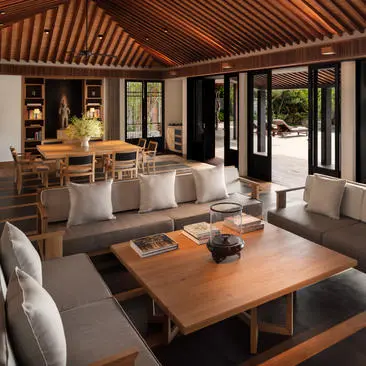 Living area of a two-bedroom ocean pool residence at Amanoi, Vietnam, with wooden dining table, grey seating and views to the terrace.