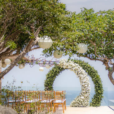 Wooden chairs beneath flowering vines at Amanoi, with ocean view beyond.