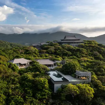 Aerial view of four-bedroom ocean pool family residence at Amanoi, Vietnam, nestled among lush vegetation with mountain backdrop.