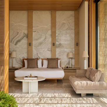Villa bedroom with marble-clad walls and daybed at Amanzoe resort.