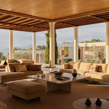 Villa accommodation at Amanzoe resort with open-plan living area, floor-to-ceiling windows and views over the landscape.