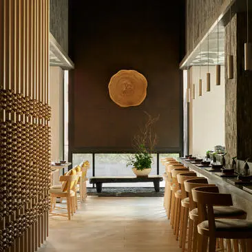 Restaurante Nama no Aman New York, com paredes de madeira clara, móveis de rattan e decoração minimalista.