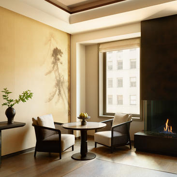 Premier Suite sitting area at Aman New York, with seating, fireplace, and city views.