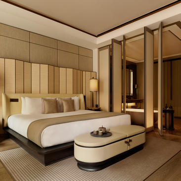 Junior suite bedroom at Aman New York featuring a bed with neutral bedding, wooden paneled walls, and contemporary furnishings.