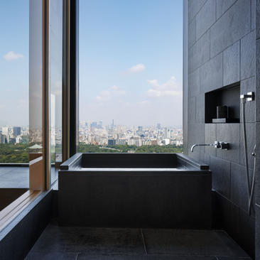 Deluxe suite bathroom at Aman Tokyo with soaking tub overlooking the city skyline.