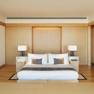 Principal bedroom at Aman Tokyo with wooden panelling, platform bed and garden views.