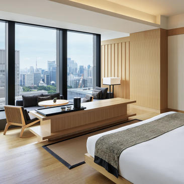 安缦东京酒店全景套房卧室，配有工作区和城市景观。
