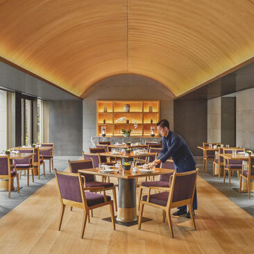 Amanyangyun dining pavilion with barrel-vaulted ceiling, round table, and floor-to-ceiling windows overlooking gardens.