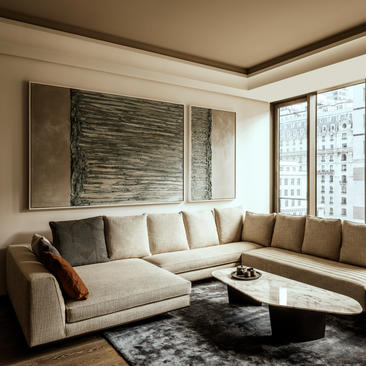 Salotto con divano angolare beige e tavolo nero presso Aman New York.