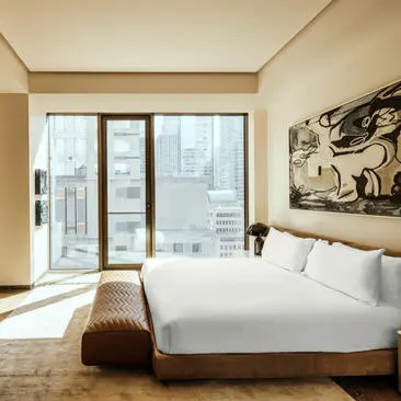 One-bedroom at Aman New York with city views, bed, and floor-to-ceiling windows.