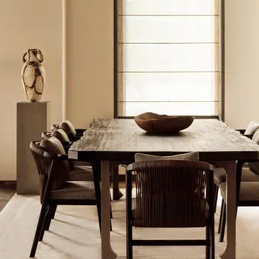 Three-bedroom dining area at Aman New York with dark wood table, sculptural chairs, and natural light from large windows.