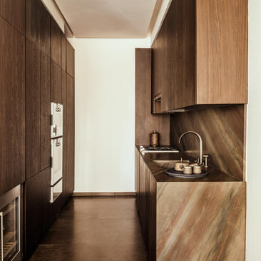 Cucina di una camera con una camera da letto presso Aman New York, con armadi in legno scuro e banco in legno chiaro.