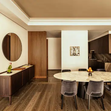 One-bedroom living room at Aman New York with warm wood furnishings, round dining table, and circular mirror detail.