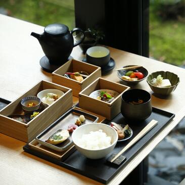 Traditional Japanese breakfast spread at Aman Kyoto, featuring small wooden compartments with seasonal dishes and tea service.