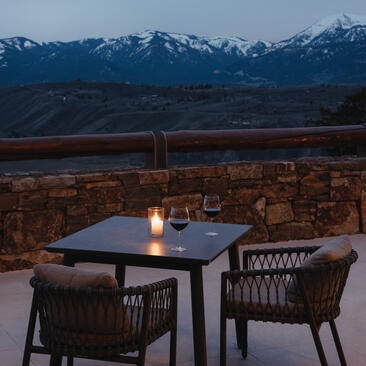 Bar seating at Amangani at dusk, overlooking snow-capped mountains and valley lights below.