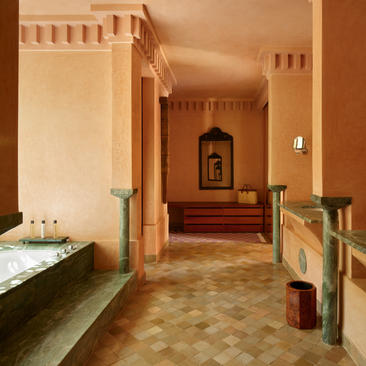 Pavillon bedroom at Amanjena resort with terracotta walls, traditional Moroccan architecture and symmetrical doorways.