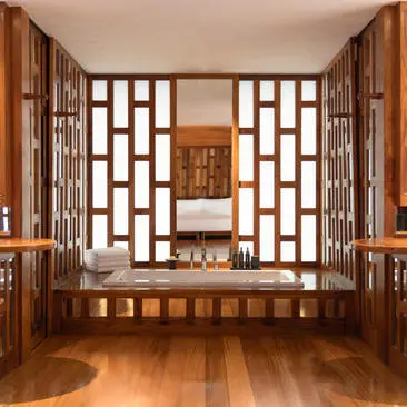 Amanpuri pavilion bathroom with geometric wooden screens and warm timber finishes.