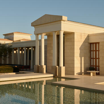 Amanzoe resort exterior with classical pavilion and reflecting pool at sunset, Greece.