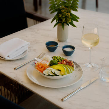 Plated dish with fresh vegetables and a glass of white wine at Amanera resort beach club, Dominican Republic.