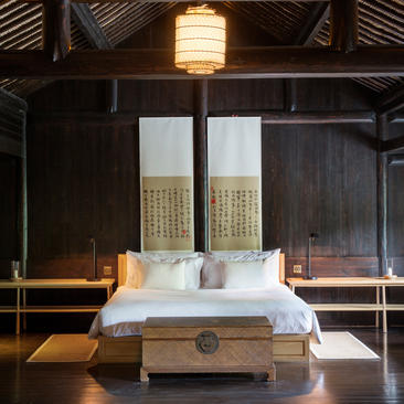 Contemporary bedroom at Amanfayun with wooden lattice doors, lantern lighting and minimal furnishings.