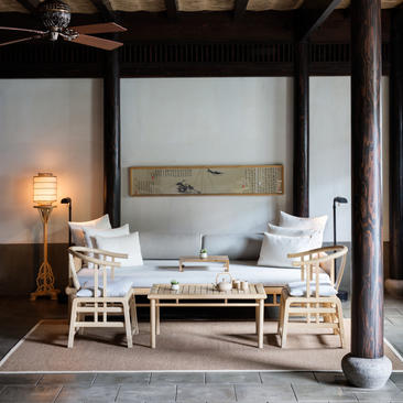 A serene bedroom at Amanfayun with a canopied bed, wooden beams, and minimalist furnishings in neutral tones.