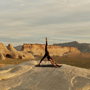 Yoga practitioner in headstand pose on terrace at Amangiri, Utah desert landscape beyond.