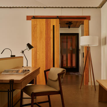 Wooden pavilion interior at Amangiri with desk, chair, and doorway leading to sleeping quarters.