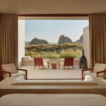 Amangiri suite with bed facing expansive window overlooking desert landscape and rock formations.