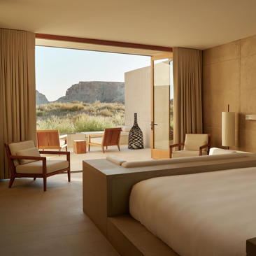 Amangiri suite with bed, seating area, and terrace overlooking desert landscape.