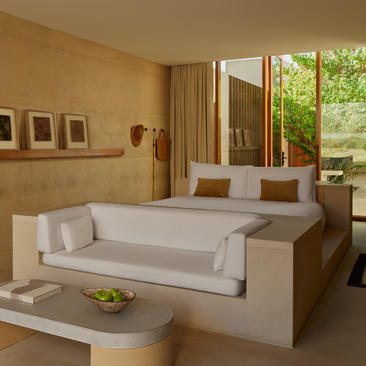 Girijaala Suite principal bedroom at Amangiri with raised bed, seated area, and garden views through expansive windows.